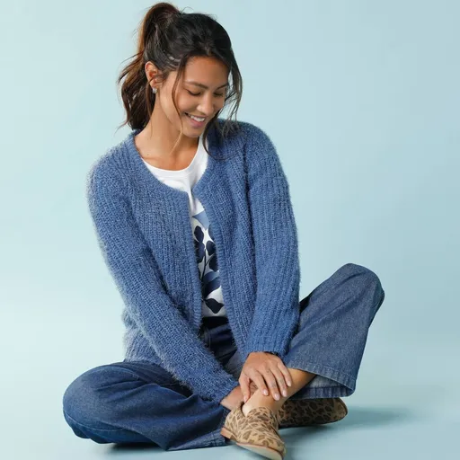 Un cardigan scurt pentru o siluetă minionă, confecționat dintr-un material pufos tricotat.